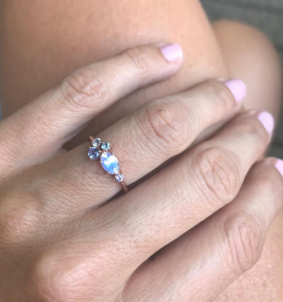 Oval moonstone cluster ring with aquamarine, sapphire, tanzanite and emerald stones