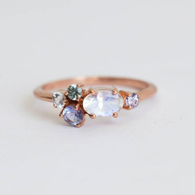 Oval moonstone cluster ring with aquamarine, sapphire, tanzanite and emerald stones