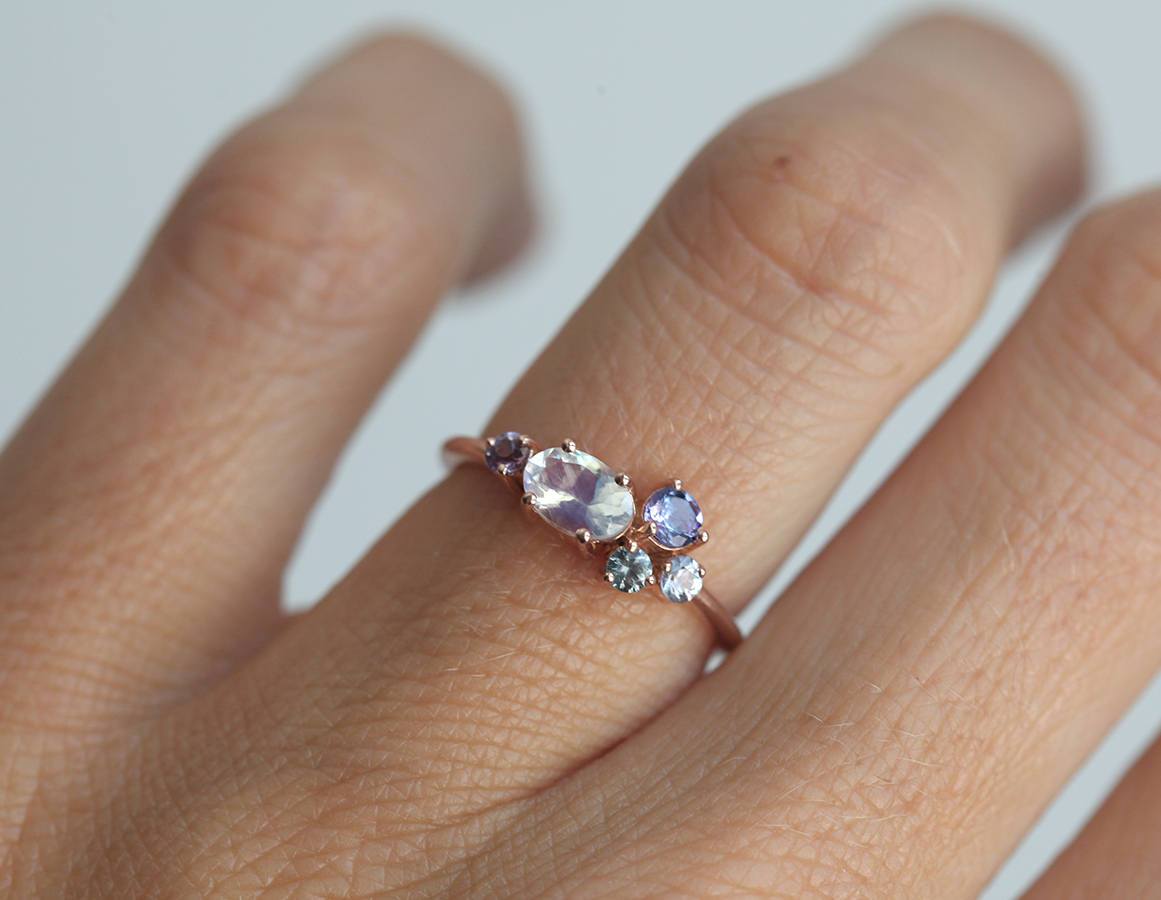 Oval moonstone cluster ring with aquamarine, sapphire, tanzanite and emerald stones