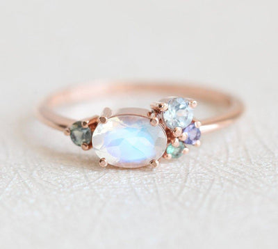 Oval moonstone cluster ring with aquamarine, sapphire, tanzanite and emerald stones