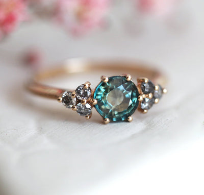 Round teal sapphire ring with salt and pepper diamond side stones