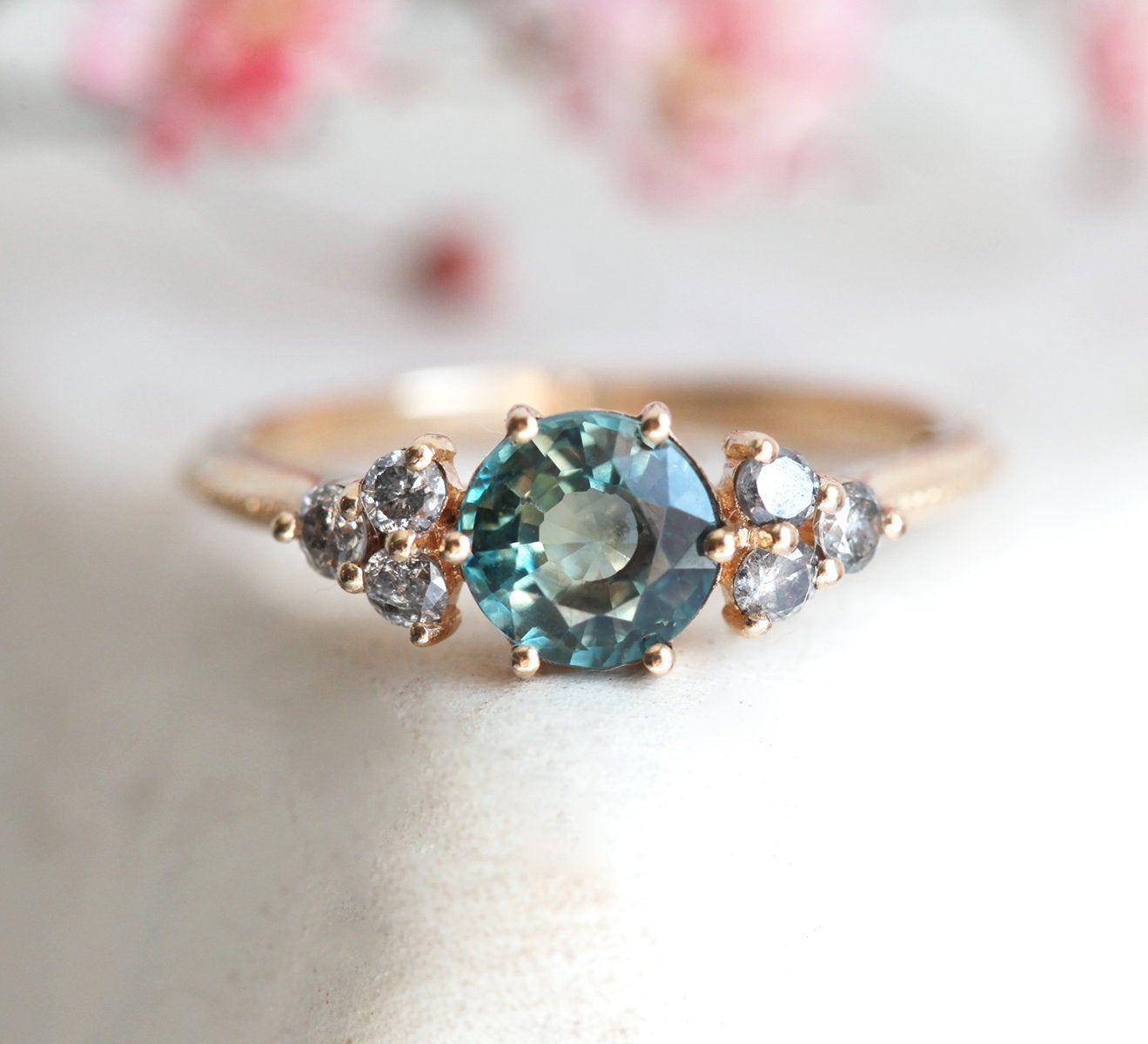 Round teal sapphire ring with salt and pepper diamond side stones