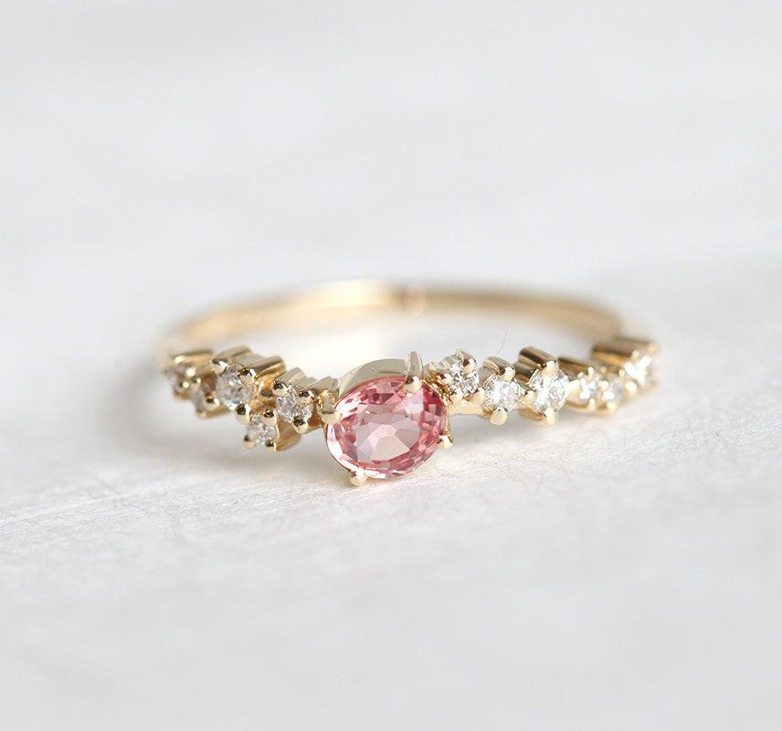 Oval-shaped peach ceylon sapphire cluster ring with diamonds