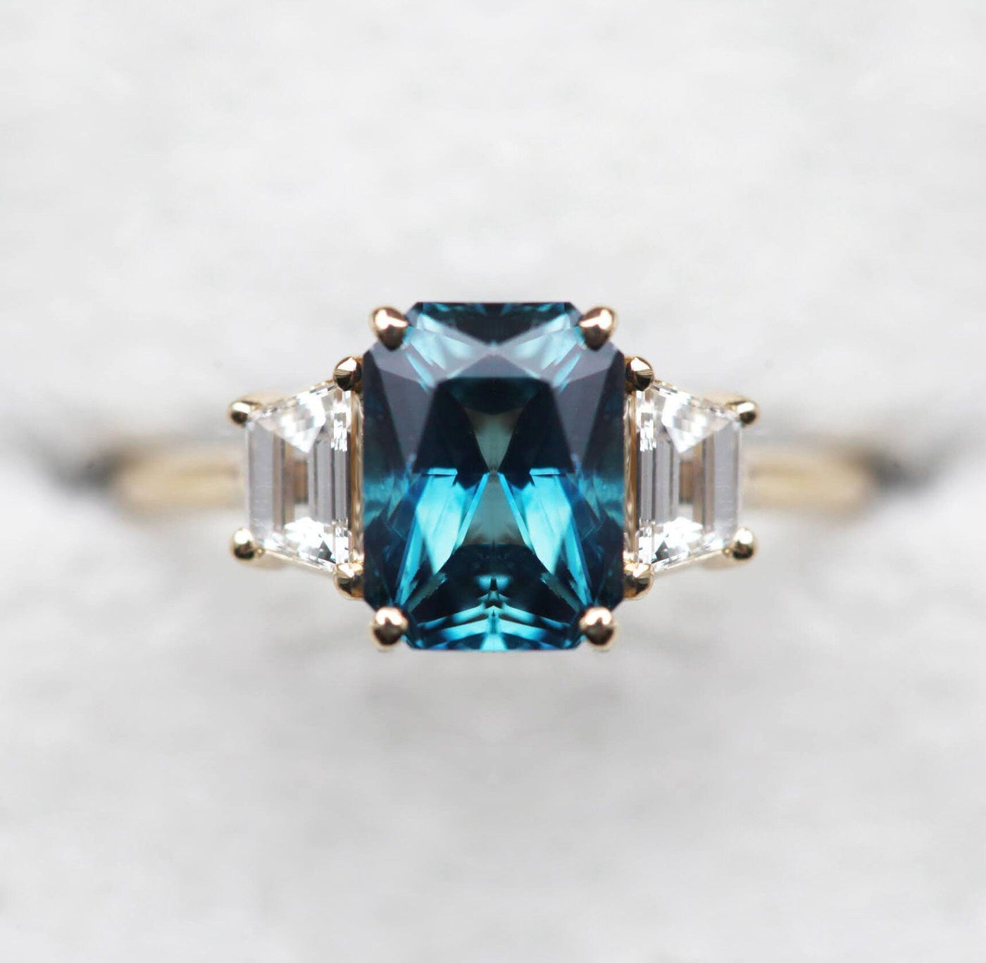 Emerald-cut blue sapphire ring with white side diamonds