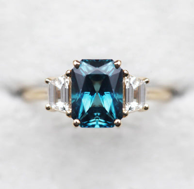 Emerald-cut blue sapphire ring with white side diamonds