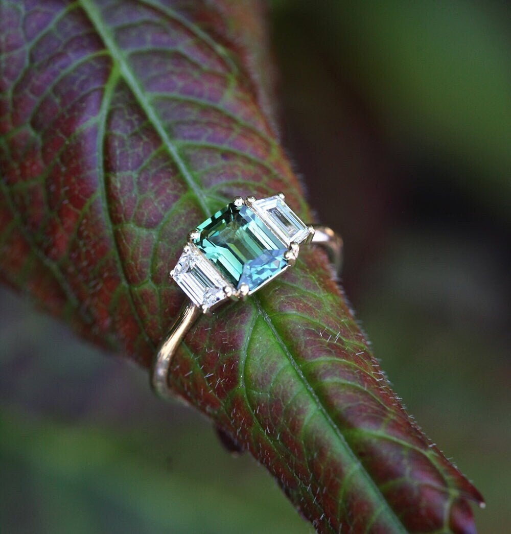 Emerald-cut blue sapphire ring with white side diamonds
