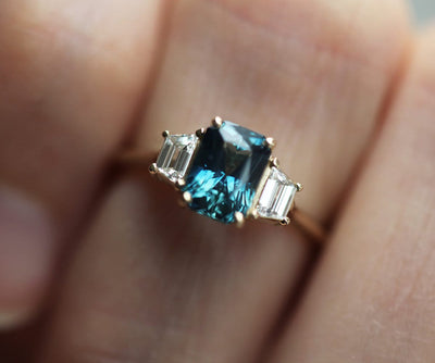 Emerald-cut blue sapphire ring with white side diamonds