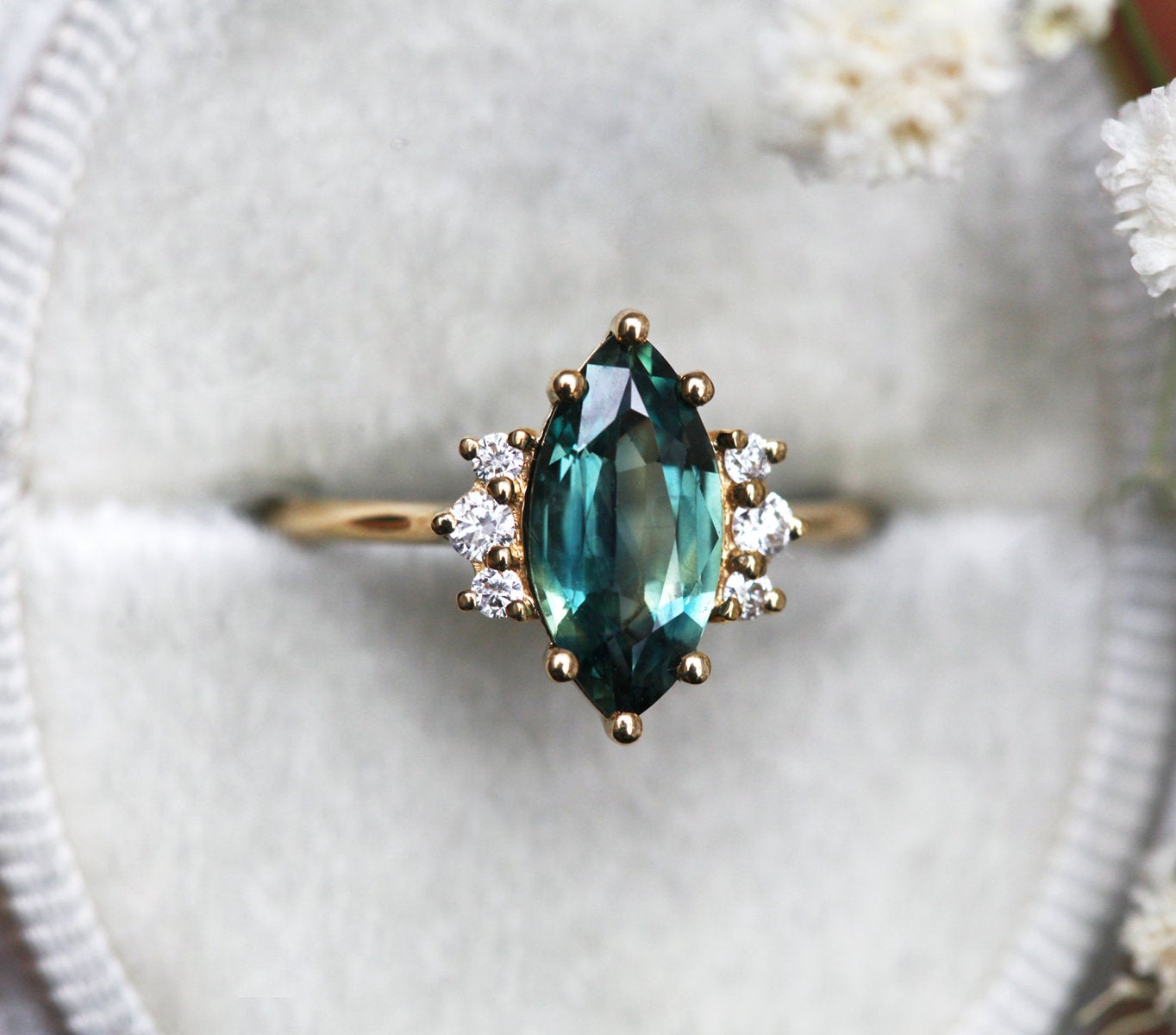 Marquise-cut teal sapphire cluster ring with white diamonds