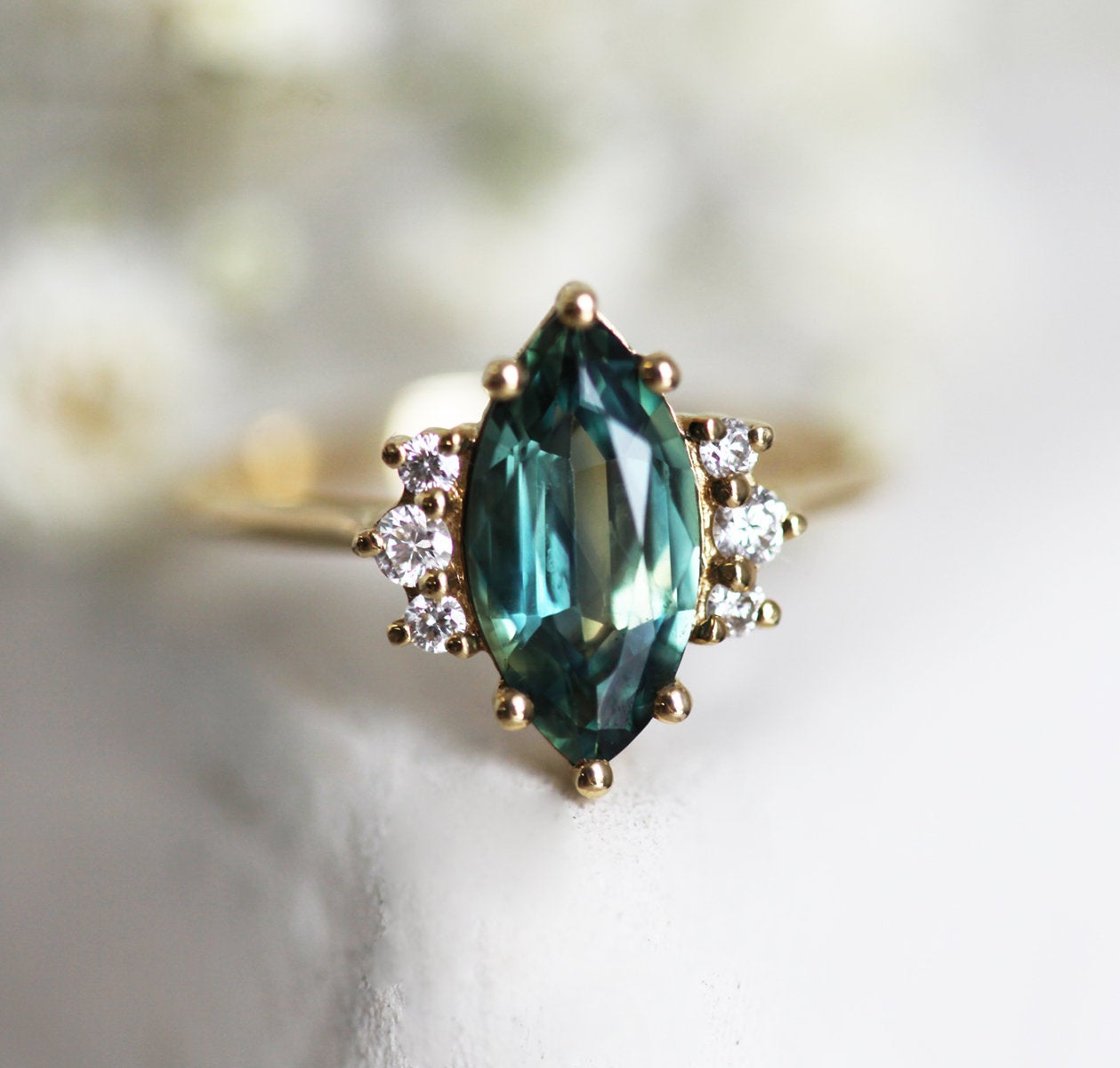 Marquise-cut teal sapphire cluster ring with white diamonds