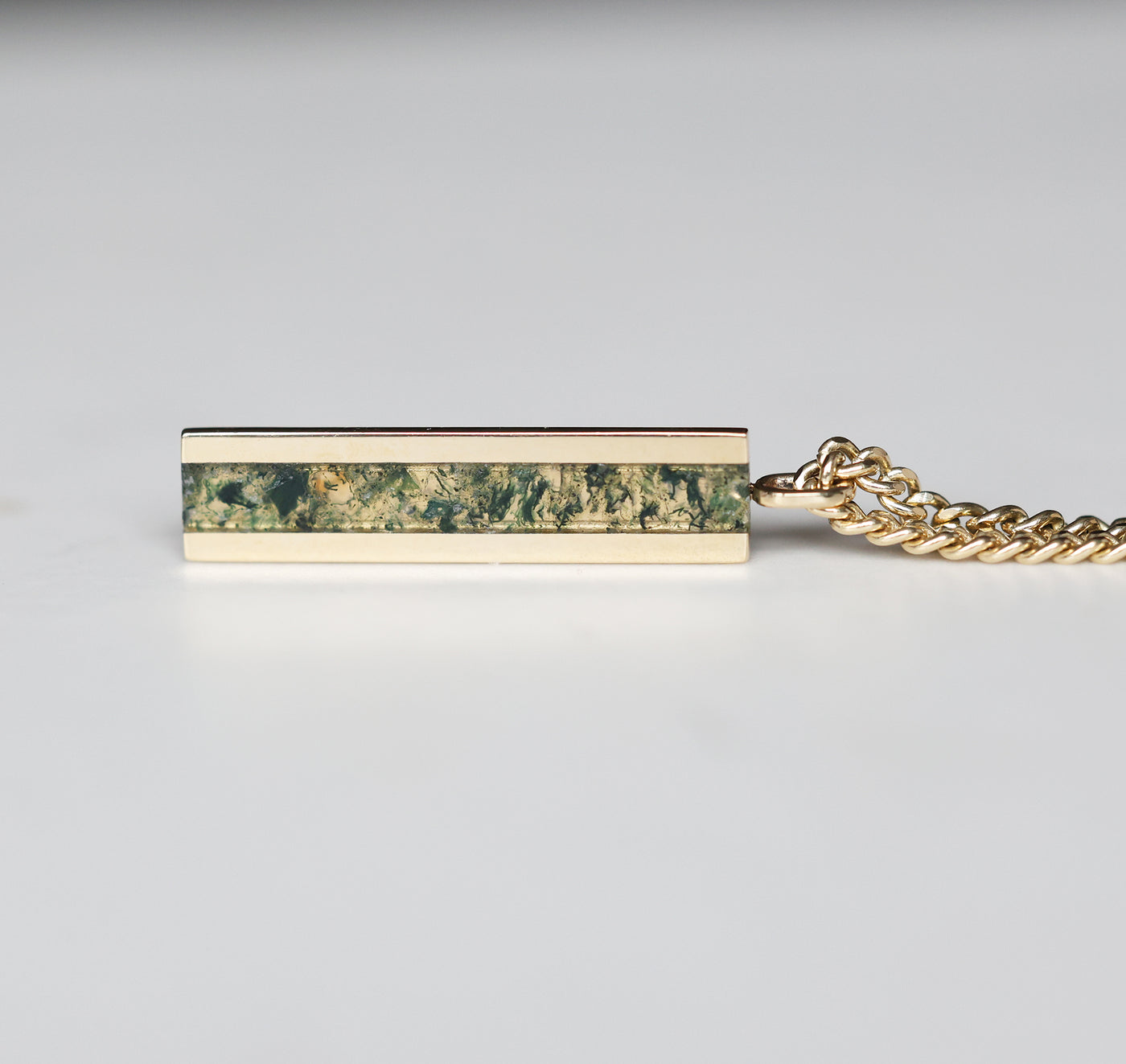 Men's bar necklace featuring a sleek 14K gold pendant with a moss agate inlay, showcasing natural green and earthy patterns on a sturdy chain.