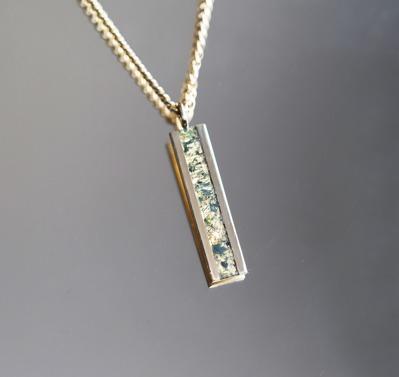 Men's bar necklace featuring a sleek 14K gold pendant with a moss agate inlay, showcasing natural green and earthy patterns on a sturdy chain.