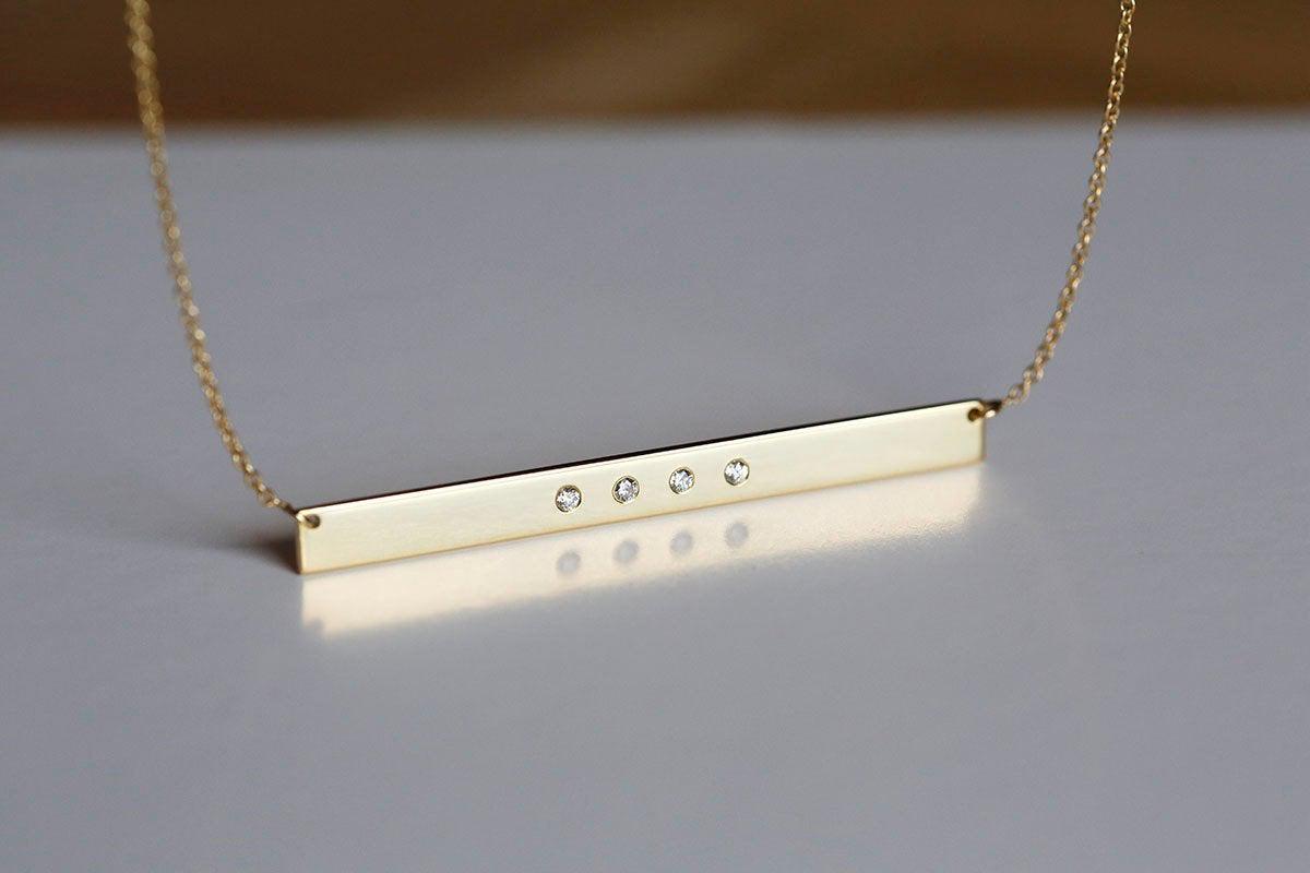 Gold bar chain necklace with four round diamonds