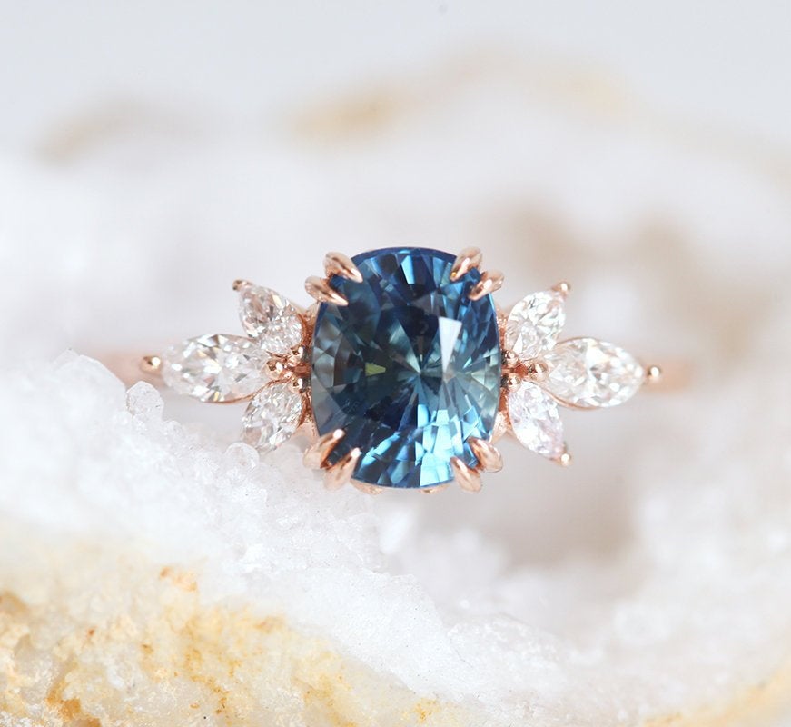 Cushion-cut blue sapphire cluster ring with white diamonds