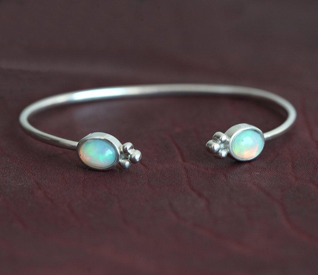 Solid gold cuffed bracelet with white oval australian opal