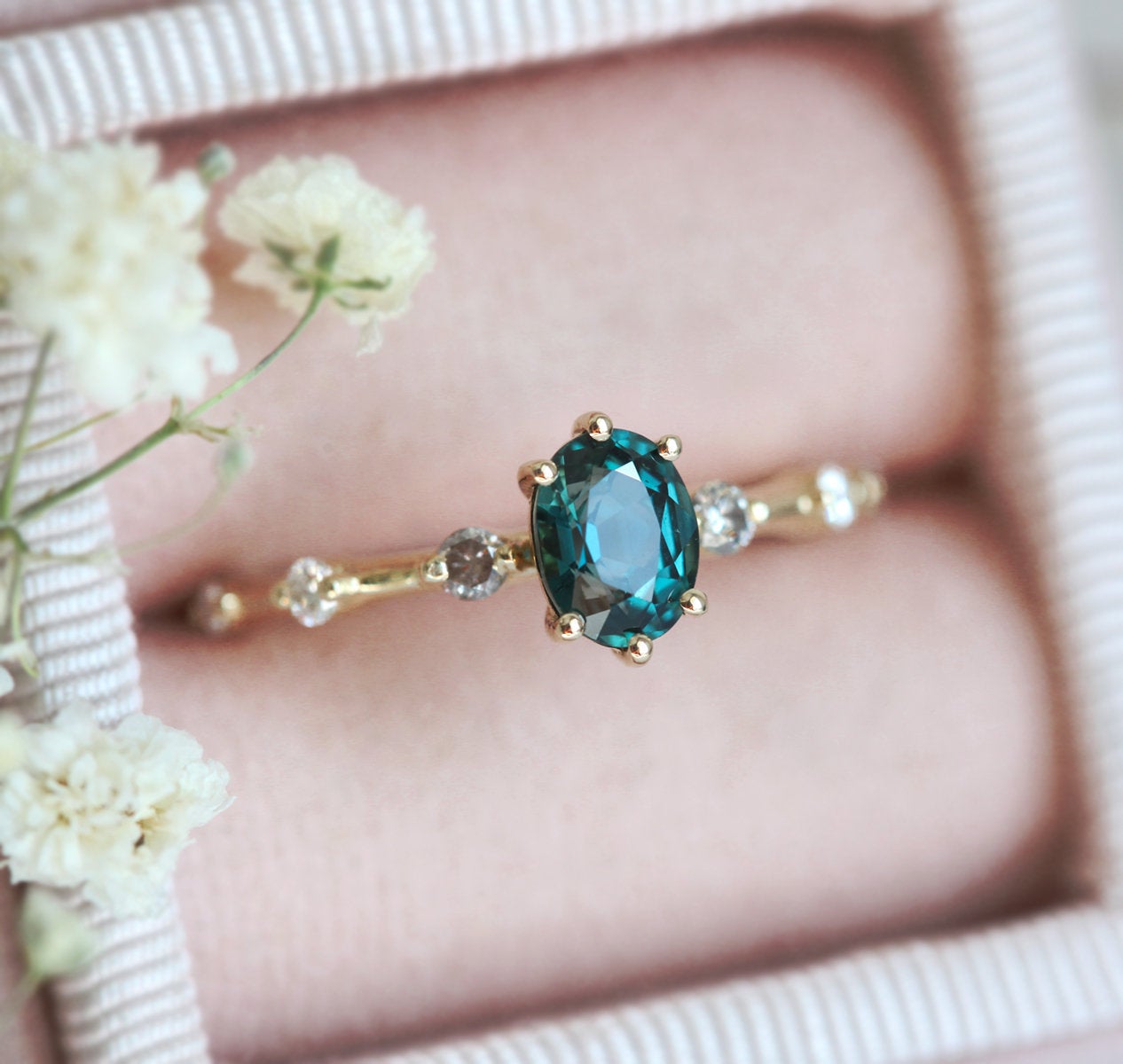 Oval-shaped teal sapphire ring with salt and pepper diamond pave