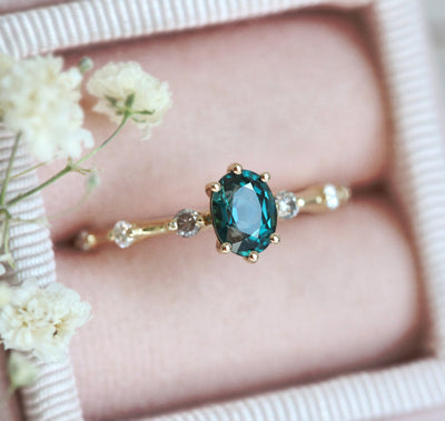 Oval-shaped teal sapphire ring with salt and pepper diamond pave
