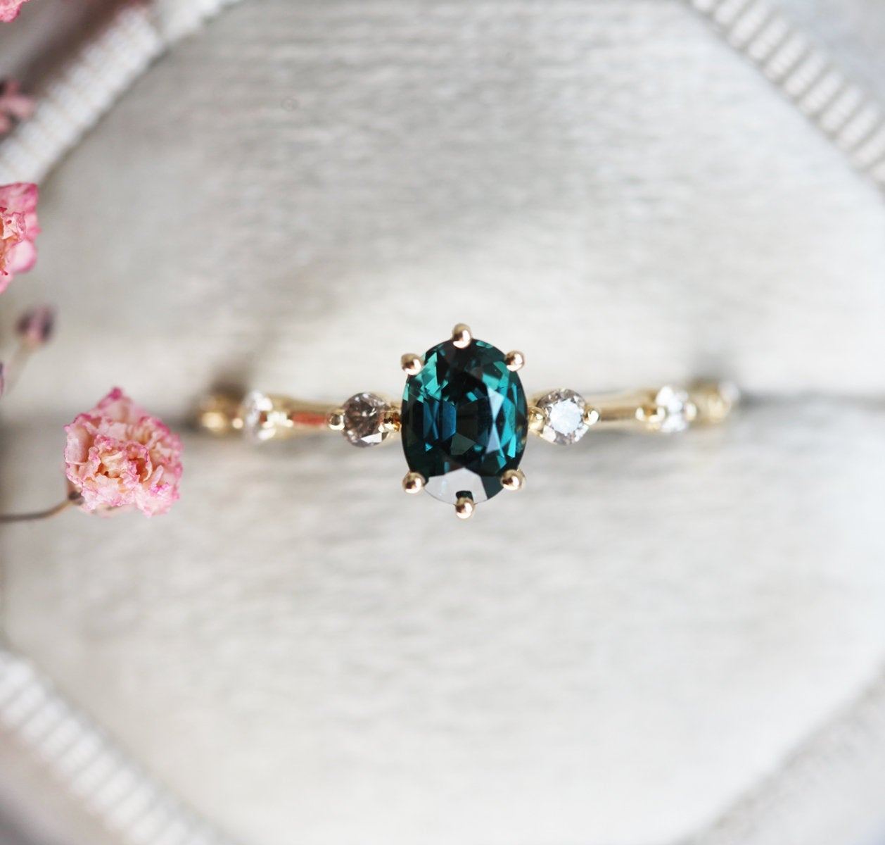 Oval-shaped teal sapphire ring with salt and pepper diamond gemstones
