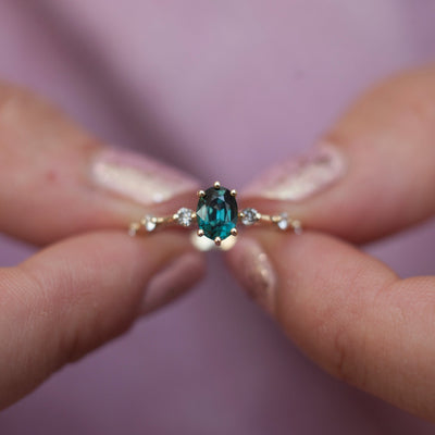 Oval-shaped teal sapphire ring with salt and pepper diamond gemstones