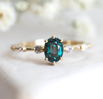 Oval-shaped teal sapphire ring with salt and pepper diamond gemstones