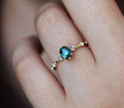 Oval-shaped teal sapphire ring with salt and pepper diamond gemstones