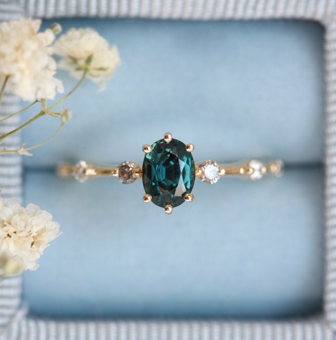 Oval-shaped teal sapphire ring with salt and pepper diamond gemstones