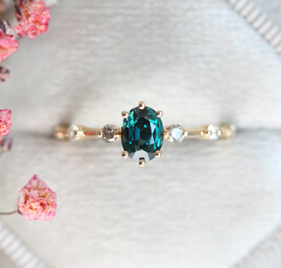 Oval-shaped teal sapphire ring with salt and pepper diamond gemstones