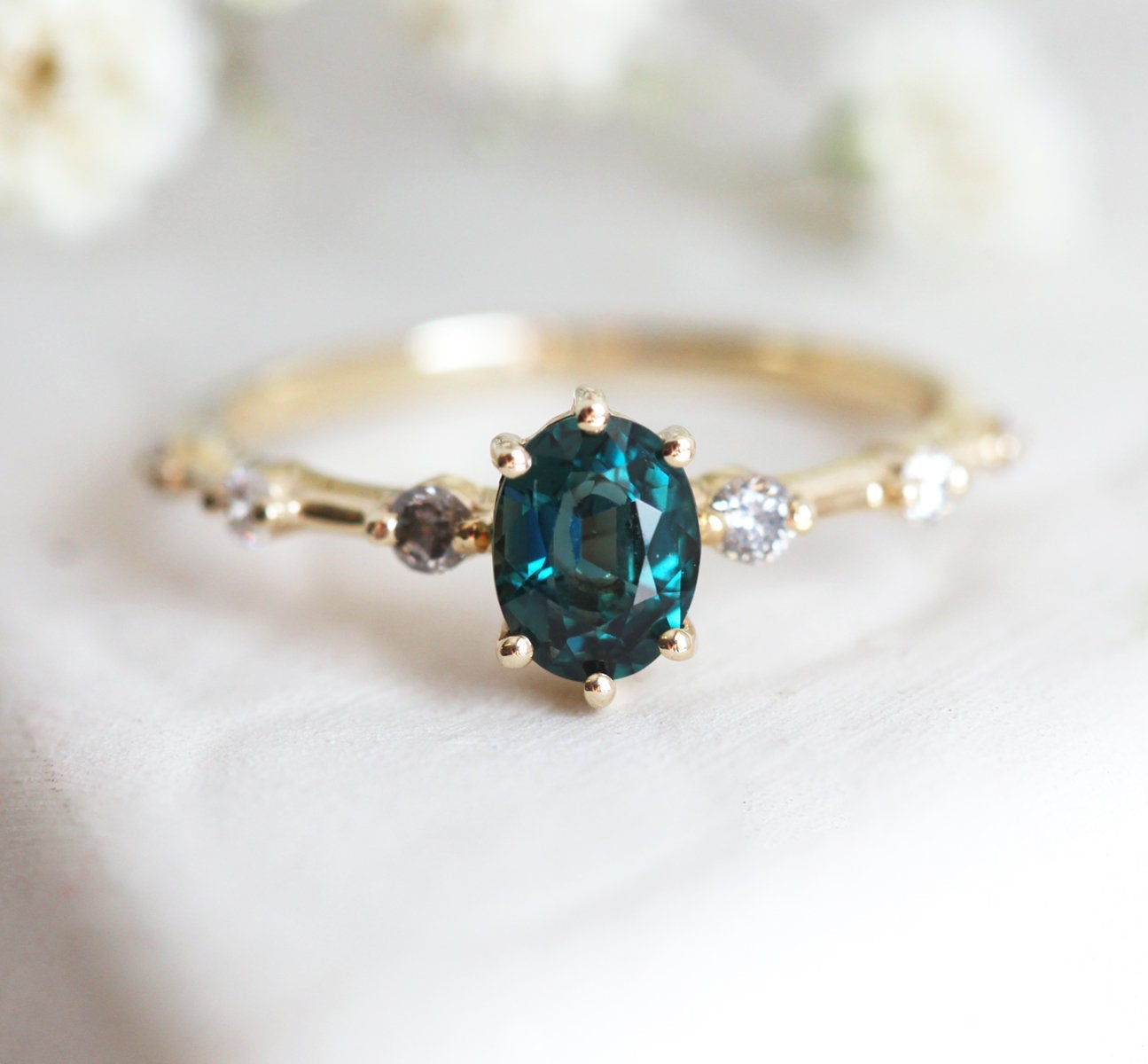 Oval-shaped teal sapphire ring with salt and pepper diamond gemstones