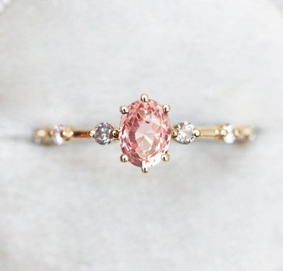 Oval-shaped pink sapphire ring with salt and pepper diamond pave