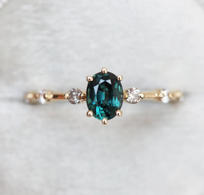 Oval-shaped teal sapphire ring with salt and pepper diamond gemstones