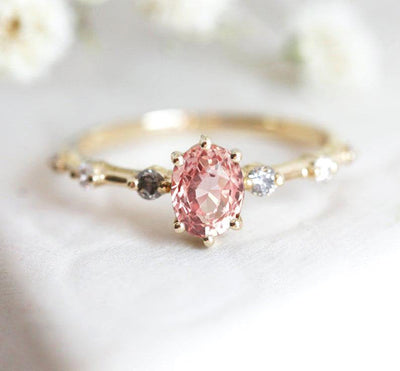 Oval-shaped pink sapphire ring with salt and pepper diamond pave