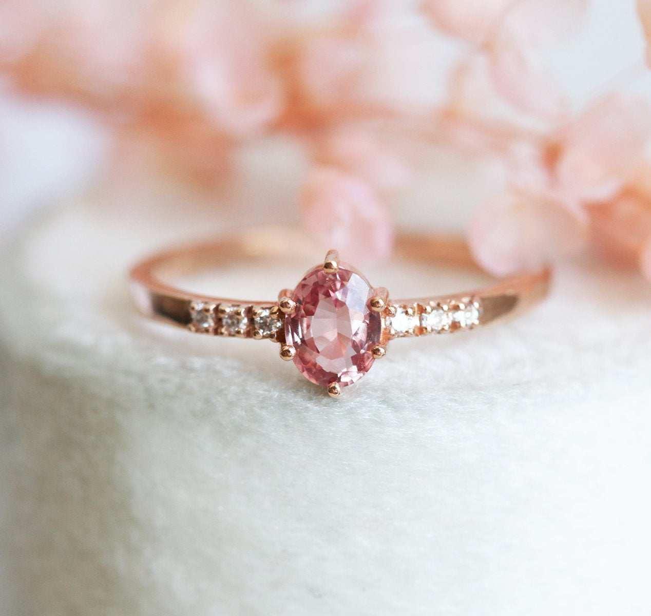 Oval peach padparadscha sapphire ring with white side diamonds