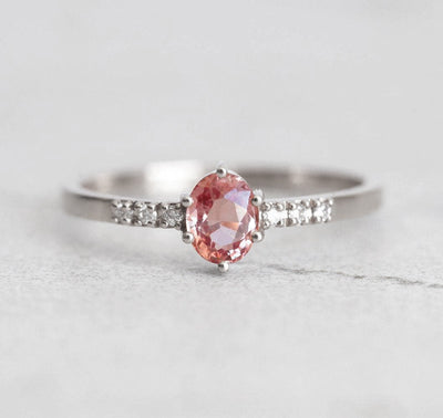 Oval peach padparadscha sapphire ring with white side diamonds