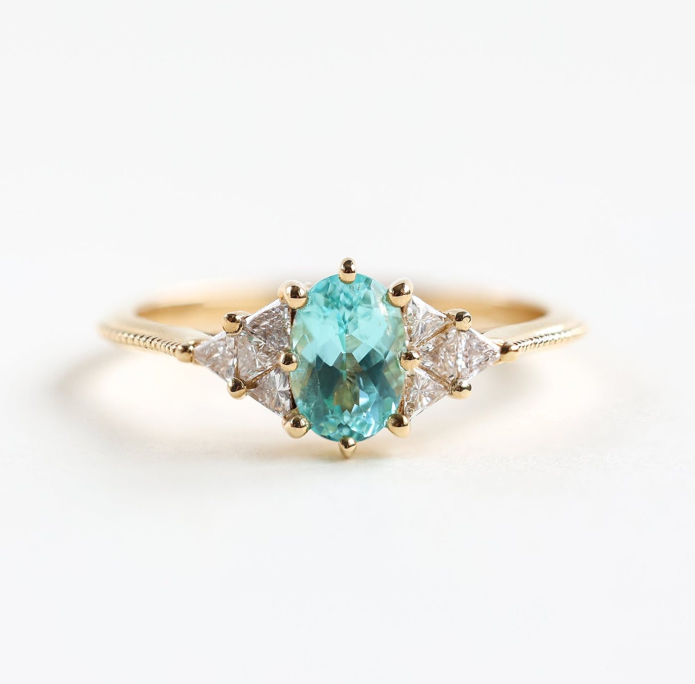 Oval Paraiba Tourmaline ring with triangle diamonds on sides, customizable gemstones available.