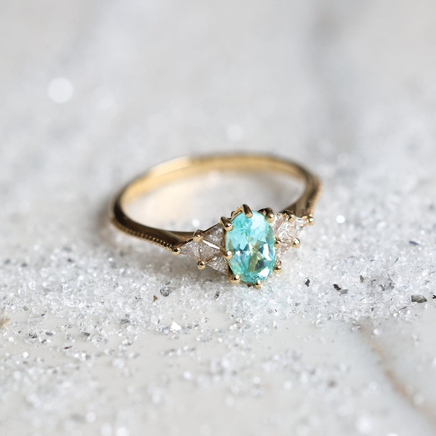 Oval Paraiba Tourmaline Engagement Ring with Triangle Diamonds on Gold Band.