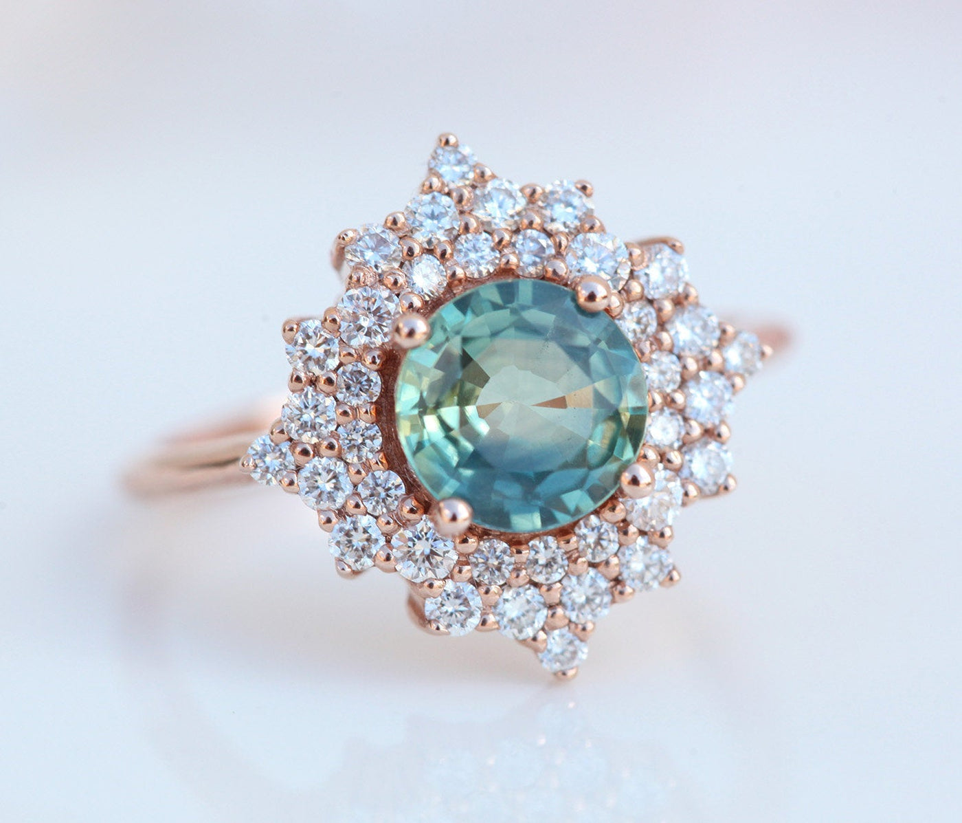 Round teal sapphire ring with diamond halo