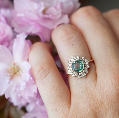 Round teal sapphire ring with diamond halo