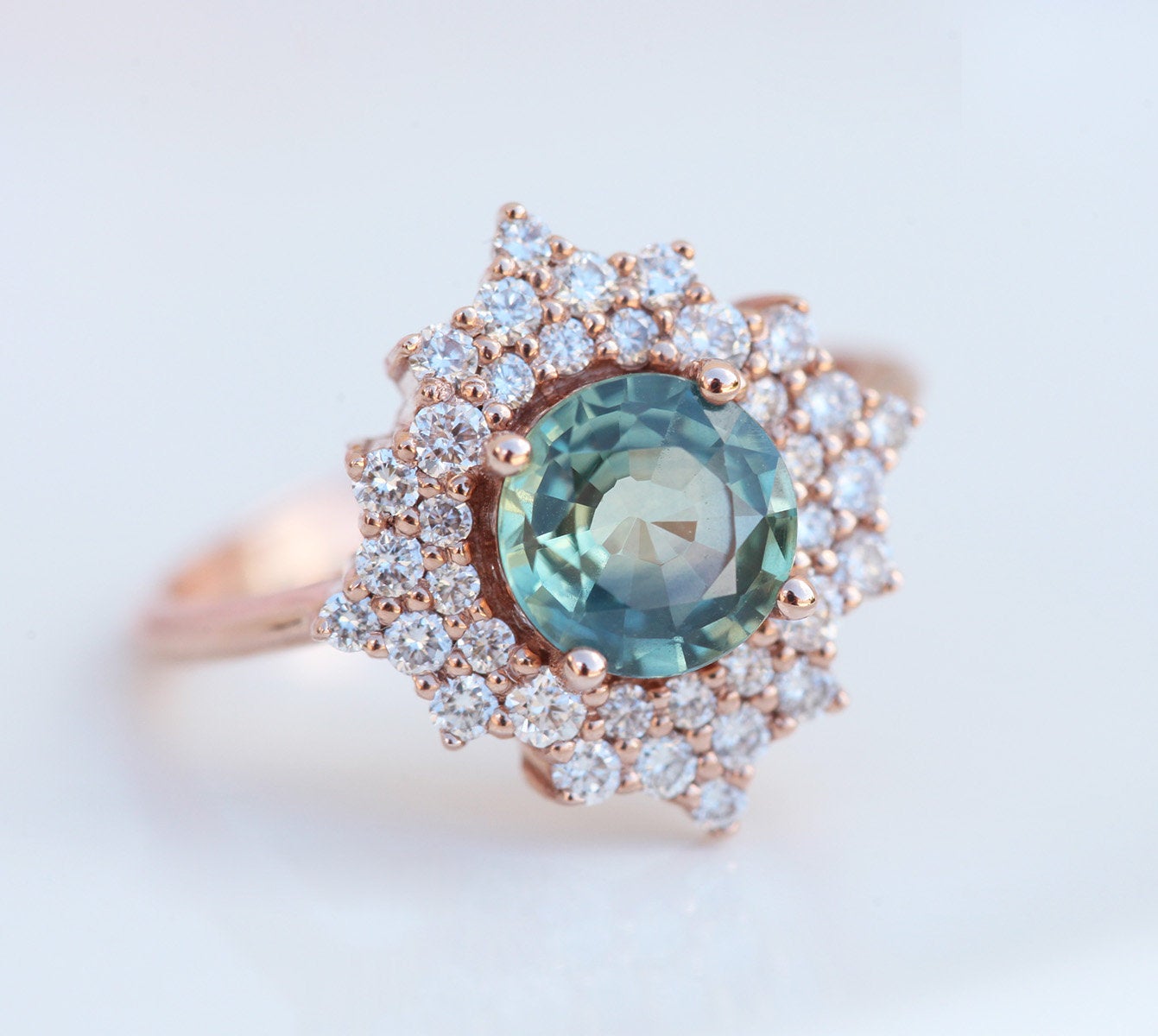 Round teal sapphire ring with diamond halo