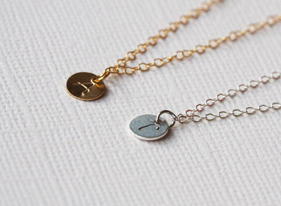 Two gold necklaces with gold discs and personalized initials