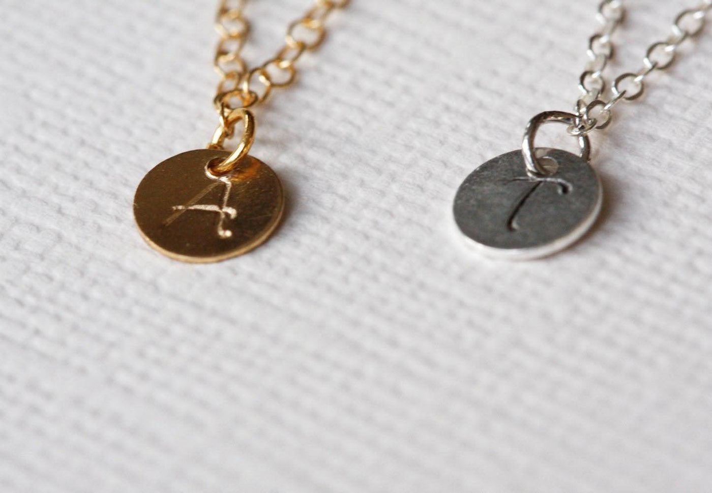 Two gold necklaces with gold discs and personalized initials