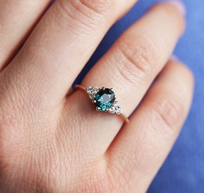 Oval-shaped teal sapphire cluster ring with diamonds