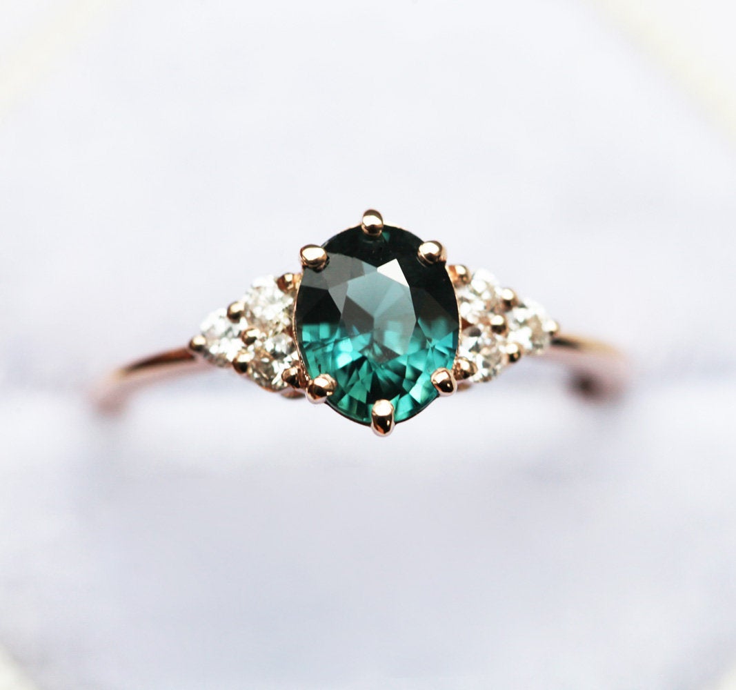 Oval-shaped teal sapphire cluster ring with diamonds