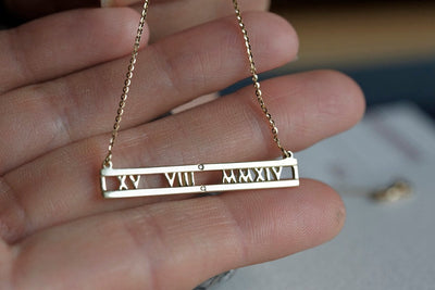 Gold chain necklace with personalized roman numerals bar and white round diamonds