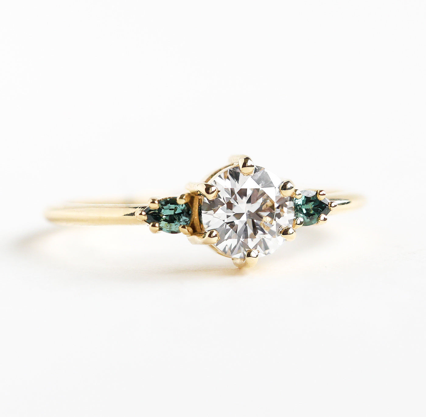 Round white diamond ring with teal pear-shaped sapphires