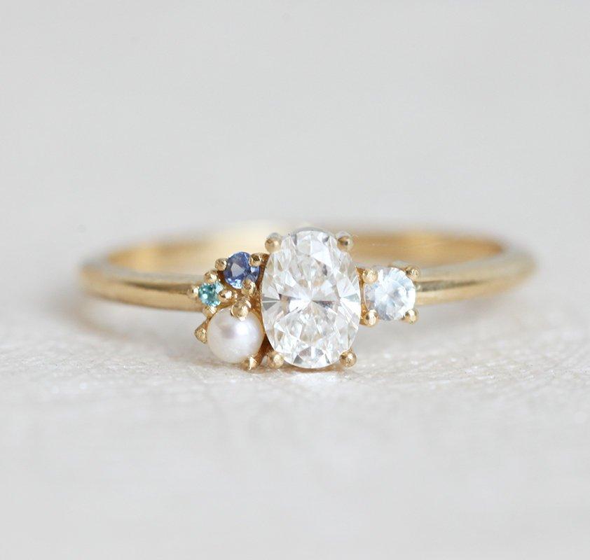 Oval-shaped diamond cluster ring with sapphire and pearl