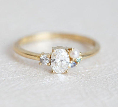 Oval-shaped diamond cluster ring with sapphire and pearl