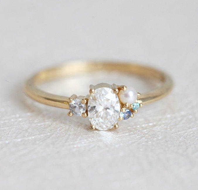 Oval-shaped diamond cluster ring with sapphire and pearl