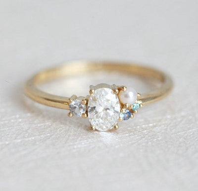 Oval-shaped diamond cluster ring with sapphire and pearl