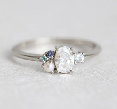 Oval-shaped diamond cluster ring with sapphire and pearl