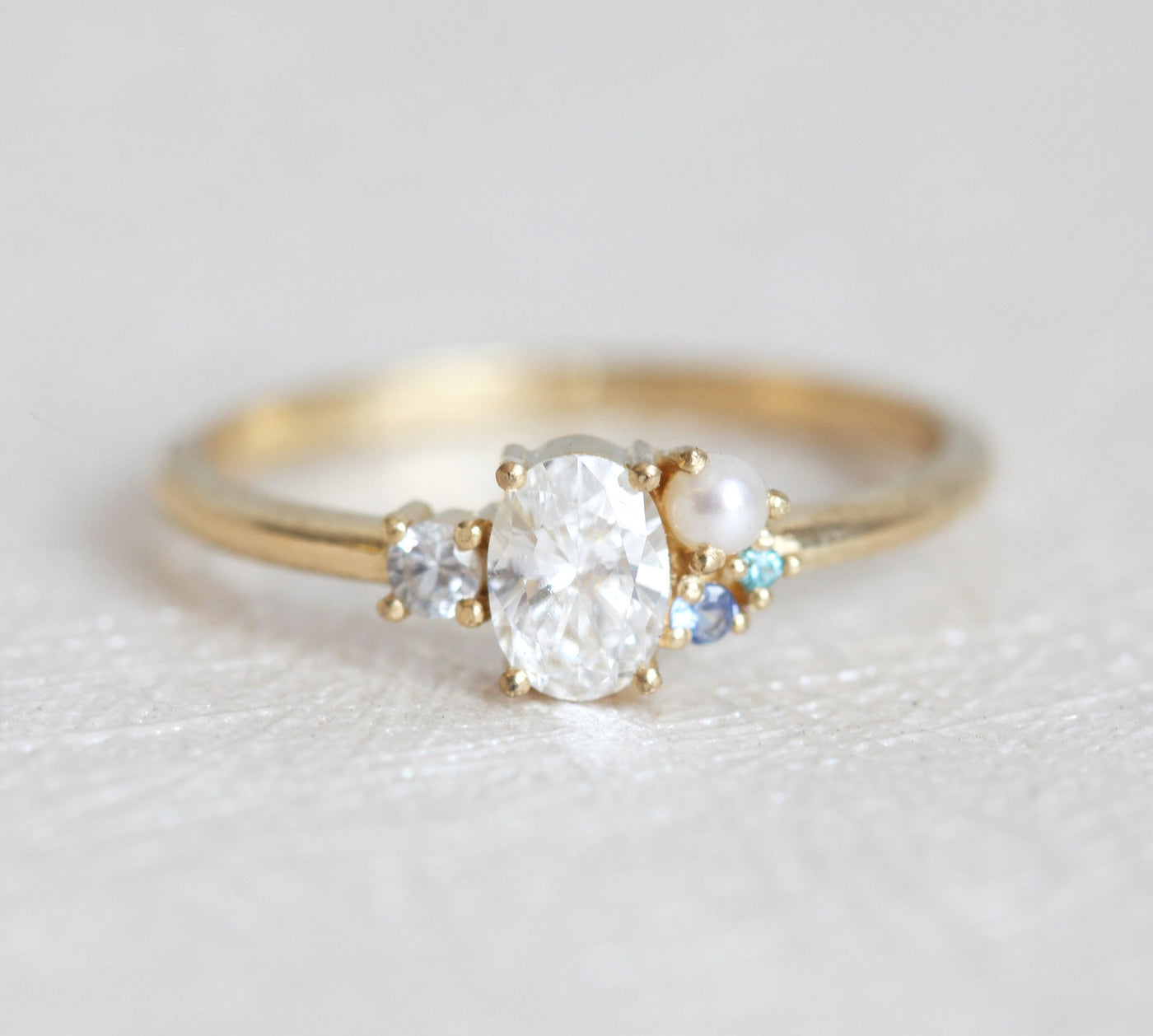 Oval-shaped diamond cluster ring with sapphire and pearl