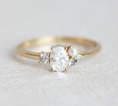 Oval-shaped diamond cluster ring with sapphire and pearl